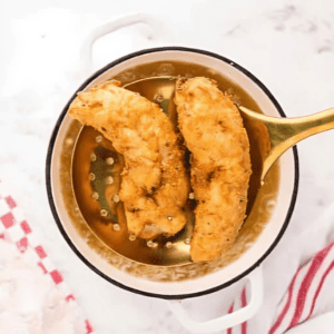 removing chicken fingers from hot oil with a strainer.