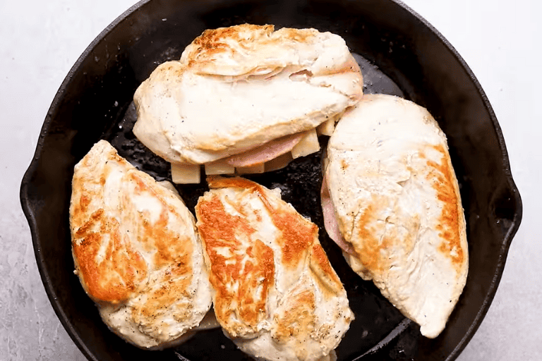 Ham and cheese stuffed chicken breasts browning in a skillet.