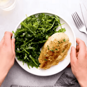 Ham and cheese stuffed chicken on a plate with a green salad.