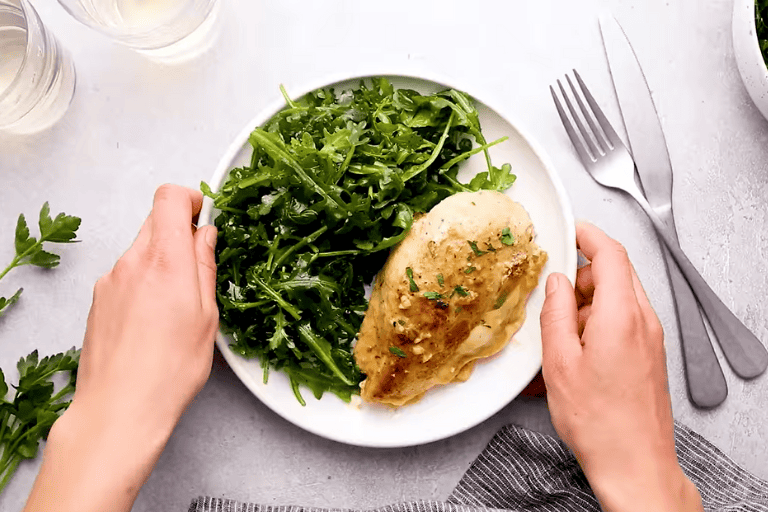 Ham and cheese stuffed chicken on a plate with a green salad.