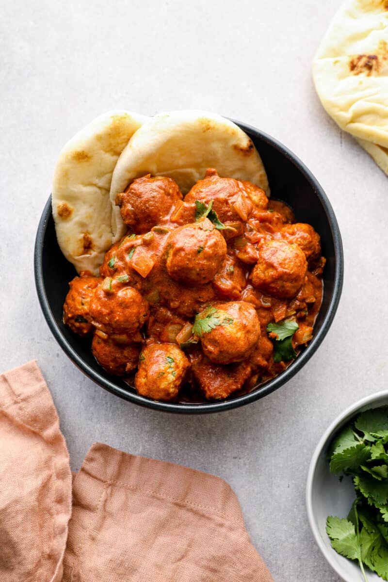 bowl of butter chicken meatballs with naan