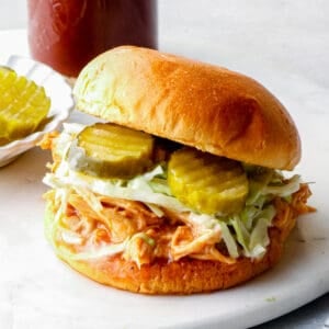 shredded bbq chicken sandwich with pickles on serving tray