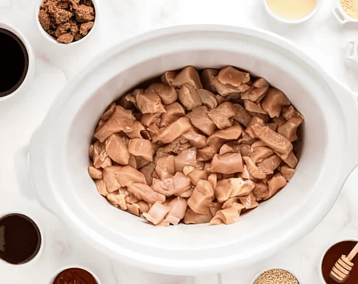 raw chicken chunks in a slow cooker.