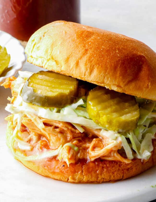 shredded bbq chicken sandwich with pickles on serving tray