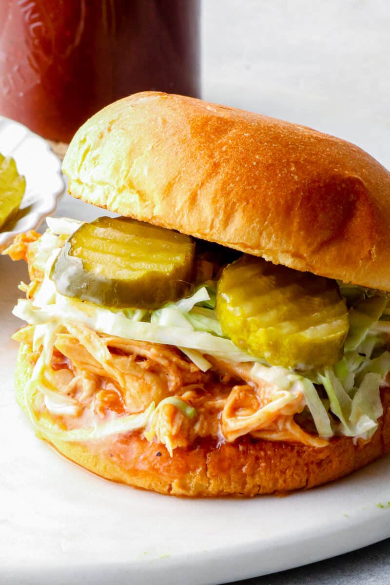 shredded bbq chicken sandwich with pickles on serving tray