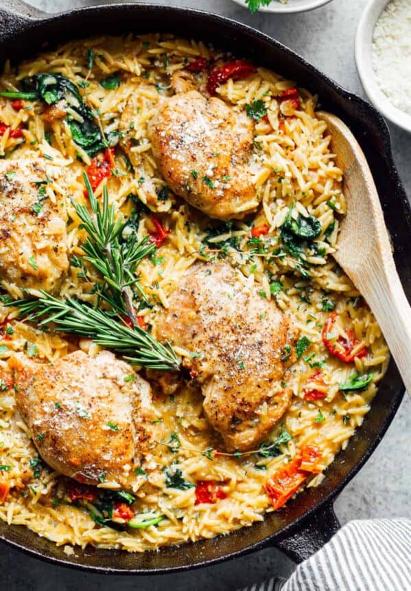 chicken risotto in a skillet with spinach and rosemary.