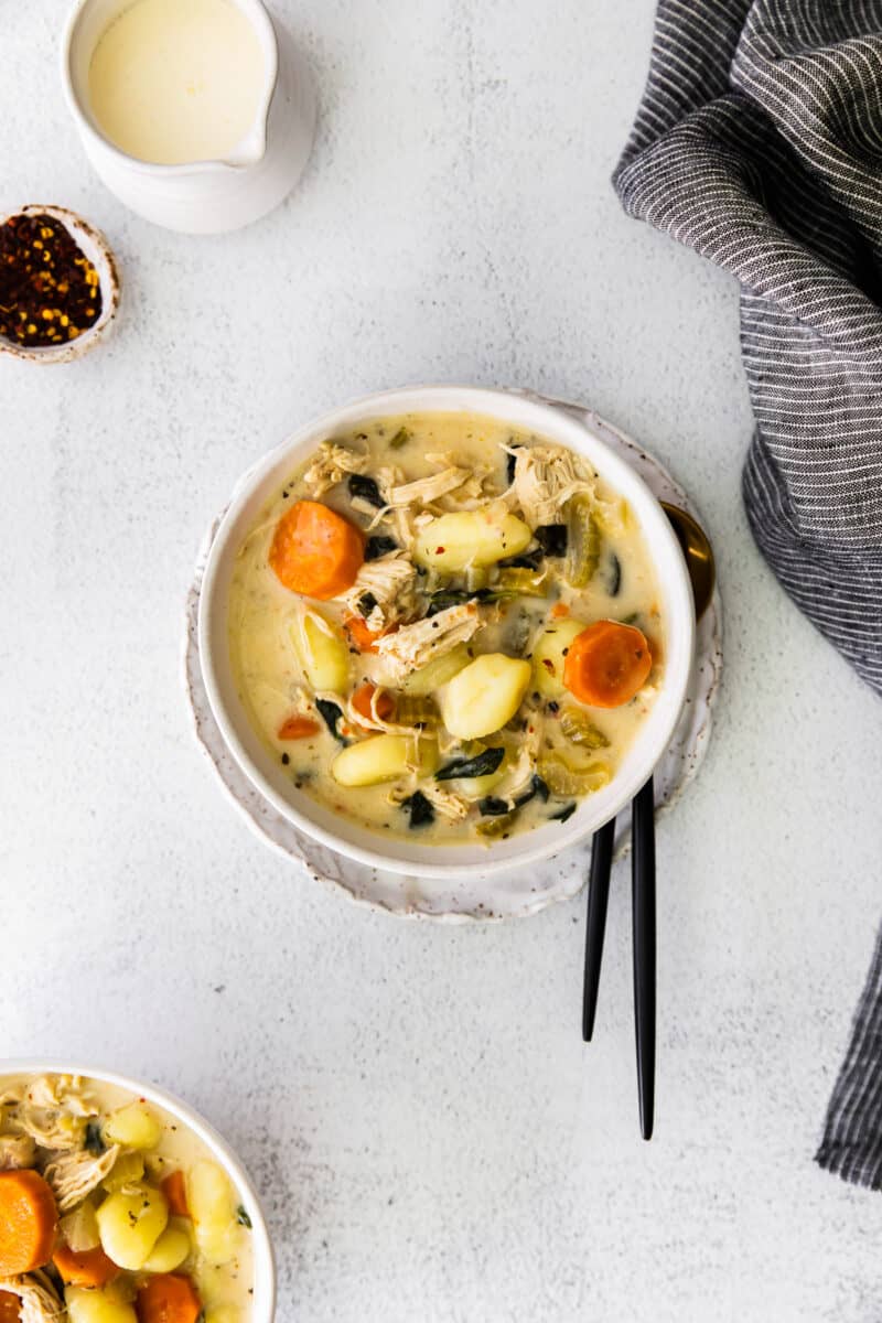 chicken gnocchi soup in a white bowl with spoons