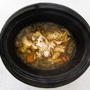 shredded chicken in a crockpot with broth and vegetables for crockpot chicken gnocchi soup