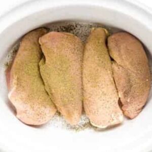 Chicken breasts in a crockpot seasoned with salt and pepper.