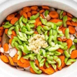 Chopped carrots, celery, and garlic in a crockpot.