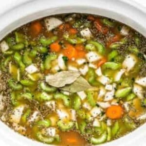 Chicken broth with chopped vegetables in a crockpot.