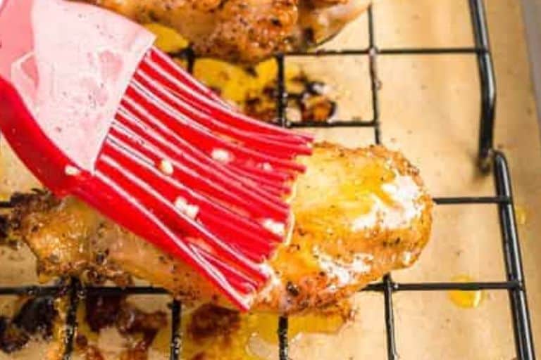 Garlic butter being brushed over garlic parmesan wings.