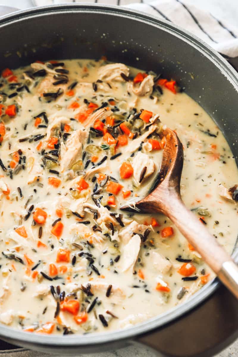 chicken wild rice soup in a pot with a wood spoon