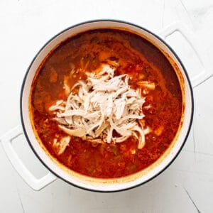 shredded chicken added to taco soup in a pot