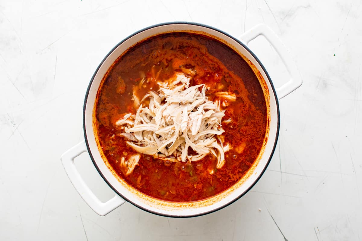 shredded chicken added to taco soup in a pot