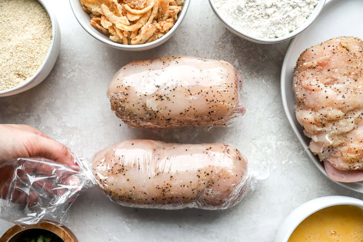 2 rolled stuffed chicken breasts tightly wrapped in plastic wrap.