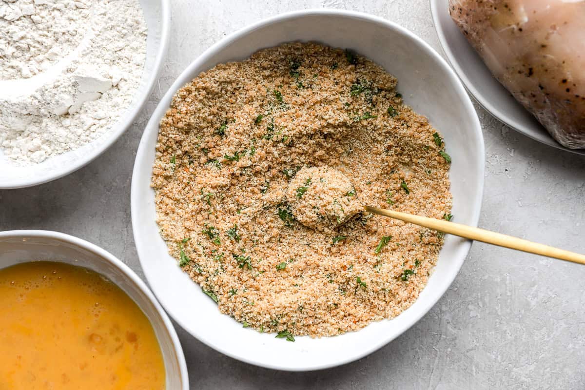 seasoned breadcrumbs in a bowl with a spoon.