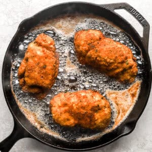 pan-frying rolled, stuffed, and breaded chicken breasts in a skillet.