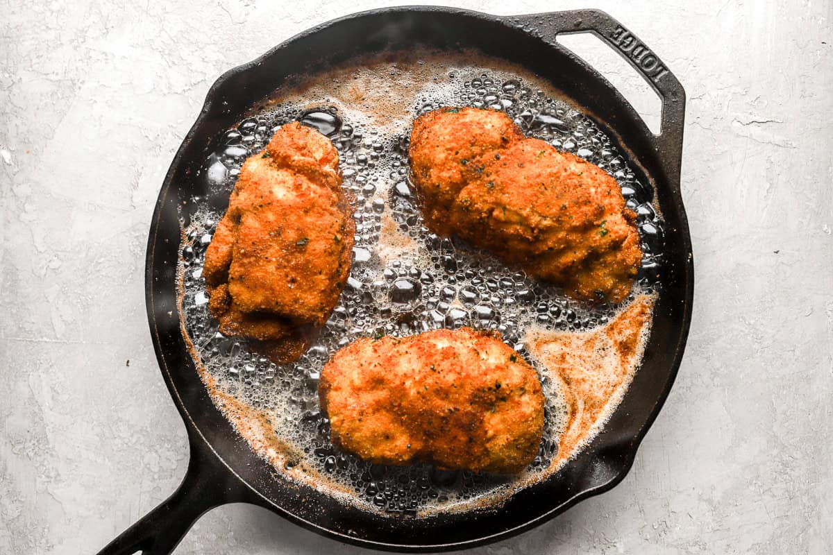 pan-frying rolled, stuffed, and breaded chicken breasts in a skillet.