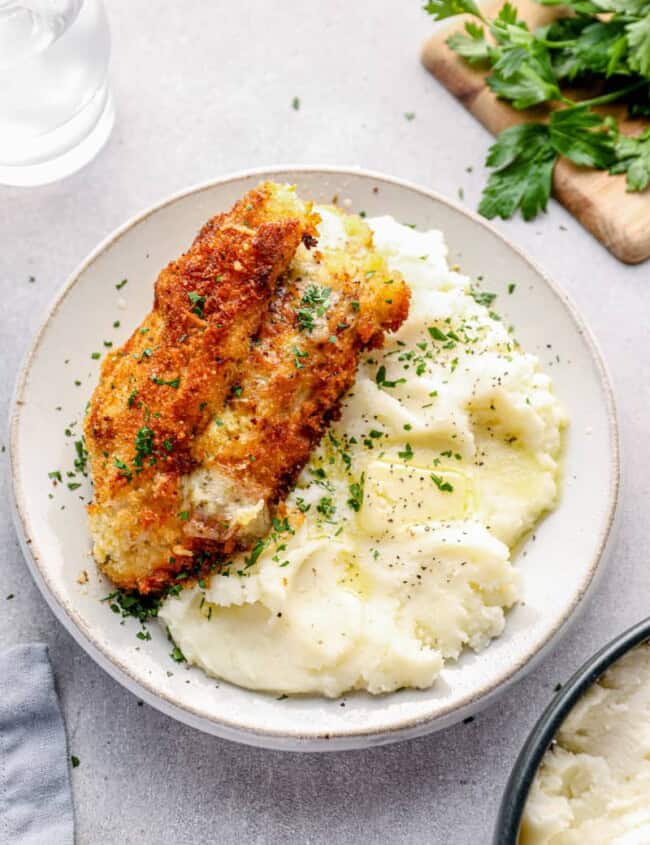 cheesy garlic stuffed chicken breast on a plate with mashed potatoes