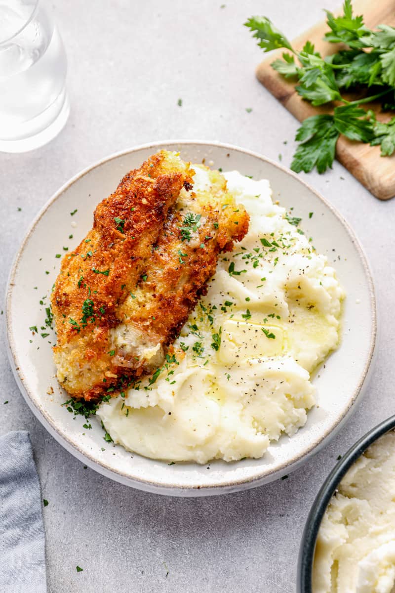 cheesy garlic stuffed chicken breast on a plate with mashed potatoes