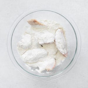 chicken wings in a glass bowl with flour coating
