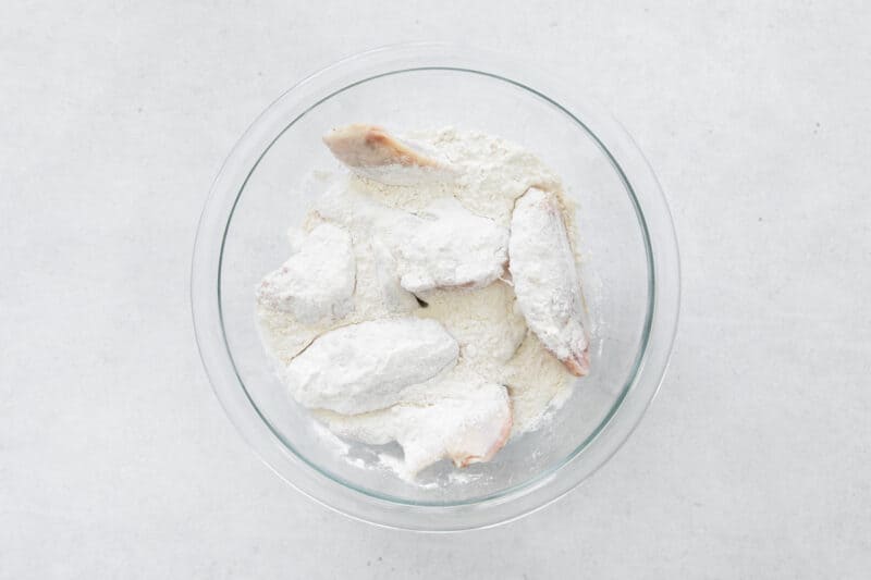 chicken wings in a glass bowl with flour coating