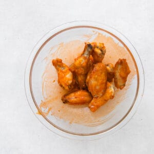 chicken wings in a glass bowl with sauce