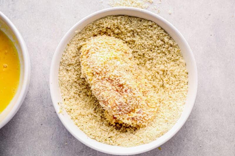 chicken breast in bowl of breadcrumbs and parmesan