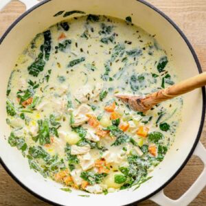 creamy chicken gnocchi soup in a white pot with a wood spoon