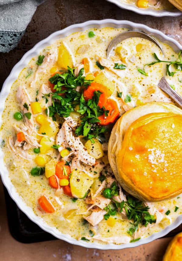 overhead view of a serving of chicken pot pie soup in a bowl with a biscuit.