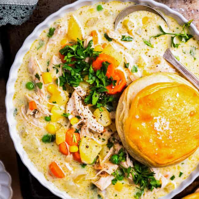 overhead view of a serving of chicken pot pie soup in a bowl with a biscuit.