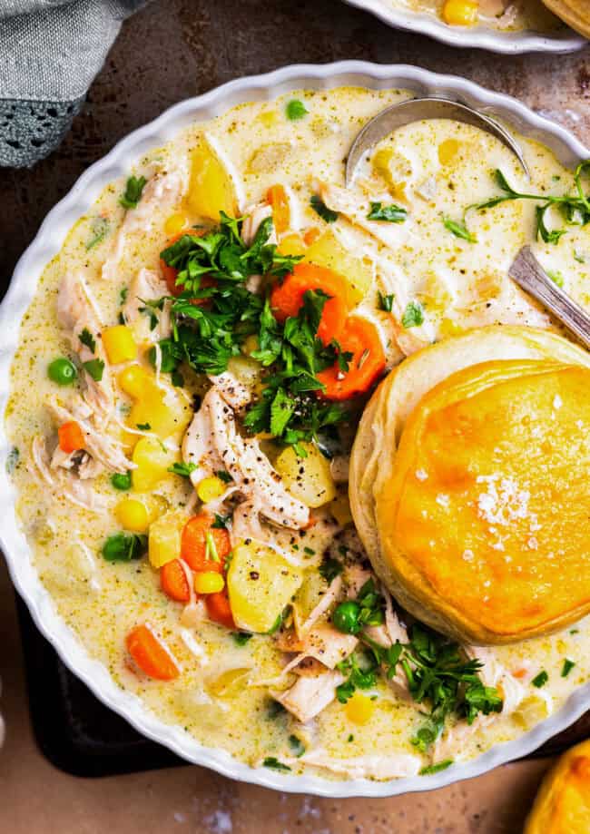 overhead view of a serving of chicken pot pie soup in a bowl with a biscuit.