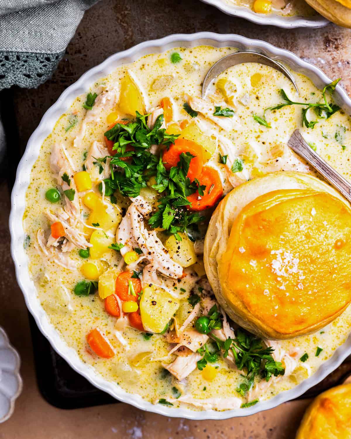 overhead view of a serving of chicken pot pie soup in a bowl with a biscuit.