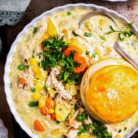 overhead view of a serving of chicken pot pie soup in a bowl with a biscuit.