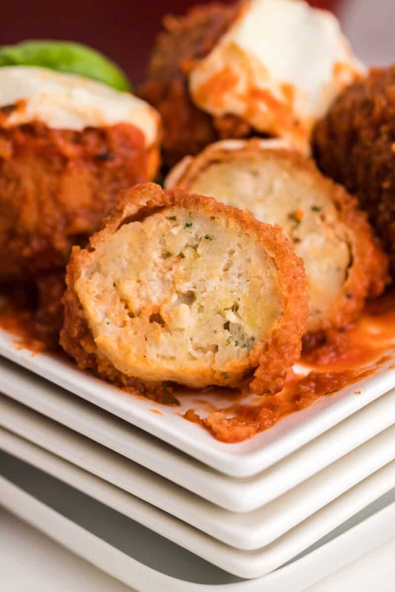 chicken meatballs on a white plate with one cut in half showing the texture