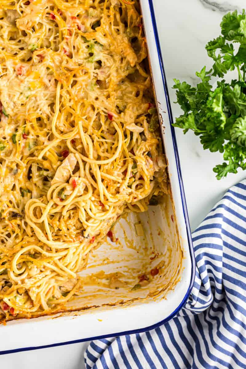 chicken spaghetti casserole in a baking dish with a serving removed