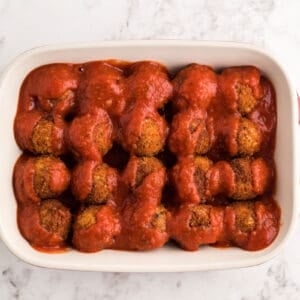 chicken parmesan meatballs in a baking dish topped with marinara sauce