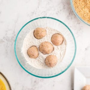 5 chicken meatballs in a bowl of flour