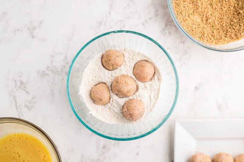 5 chicken meatballs in a bowl of flour