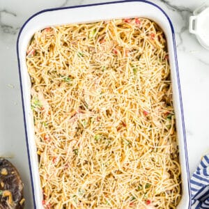 chicken spaghetti casserole topped with parmesan cheese in a baking dish before baking