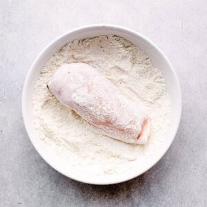 chicken breast in a bowl of flour and spices