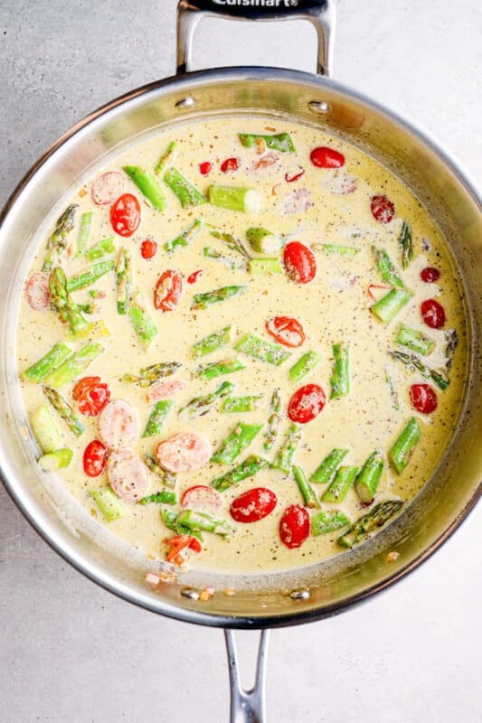 tomatoes, asparagus, and cream sauce in a skillet