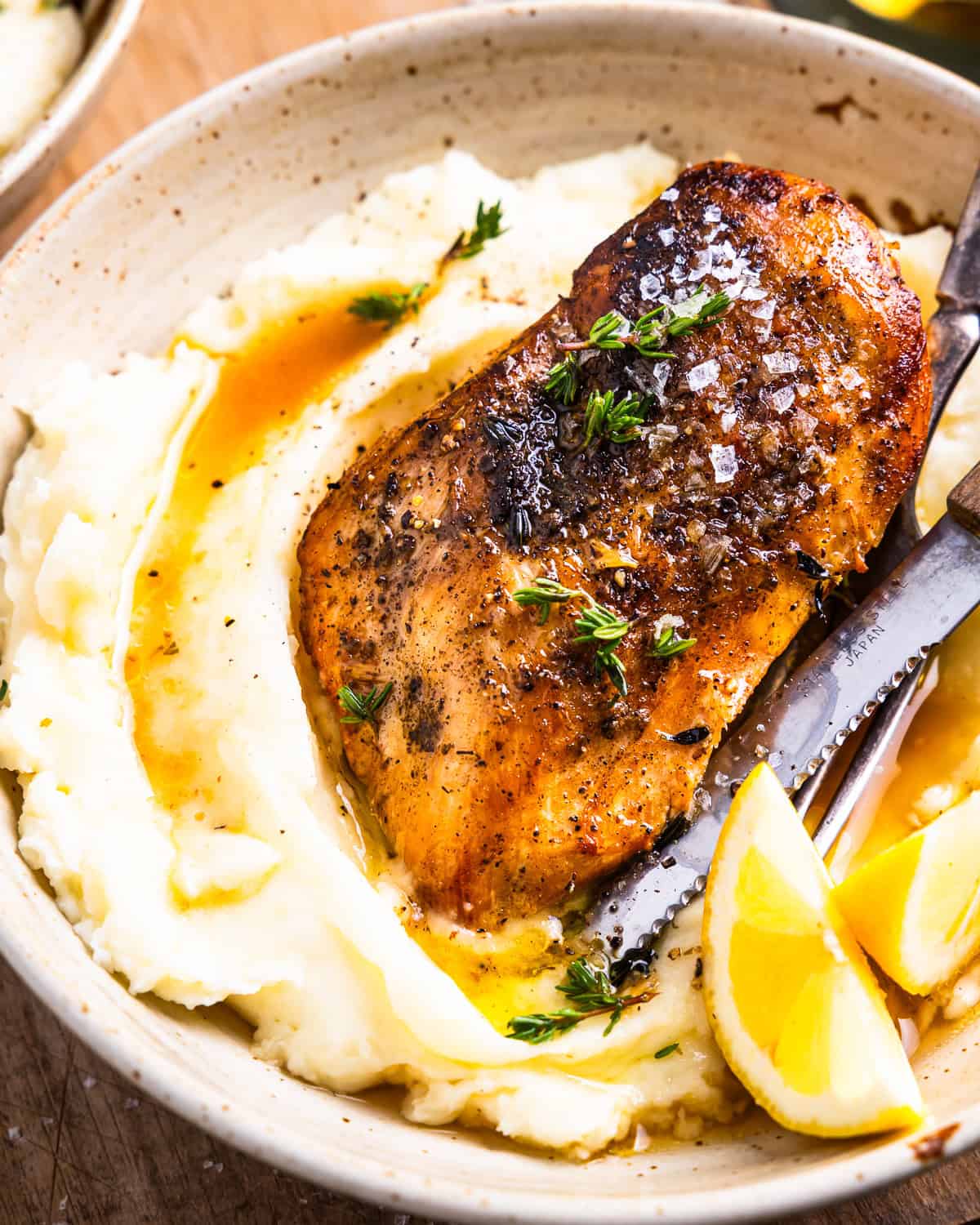 closeup view of a serving of crockpot lemon chicken over mashed potatoes.