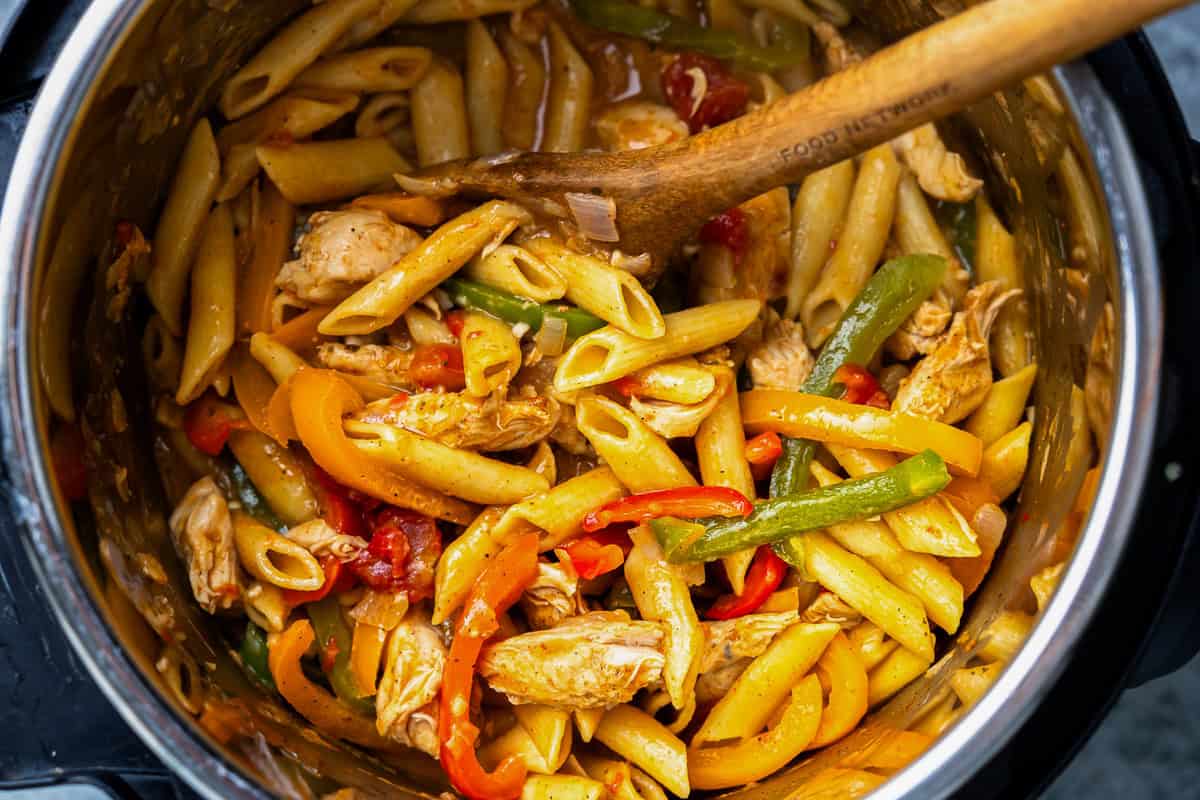 chicken fajita pasta in an instant pot with a wooden spoon.