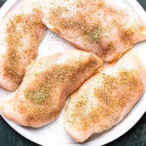 seasoned chicken breasts on a white plate.