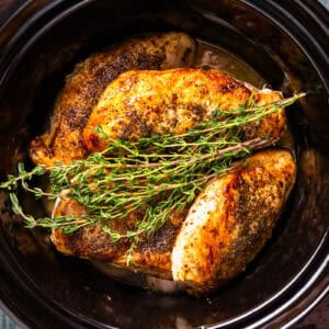 crockpot lemon chicken topped with fresh herbs in a crockpot.