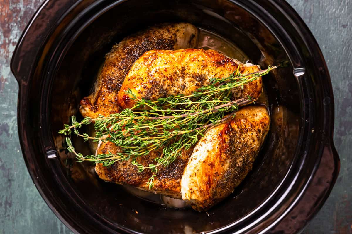 crockpot lemon chicken topped with fresh herbs in a crockpot.