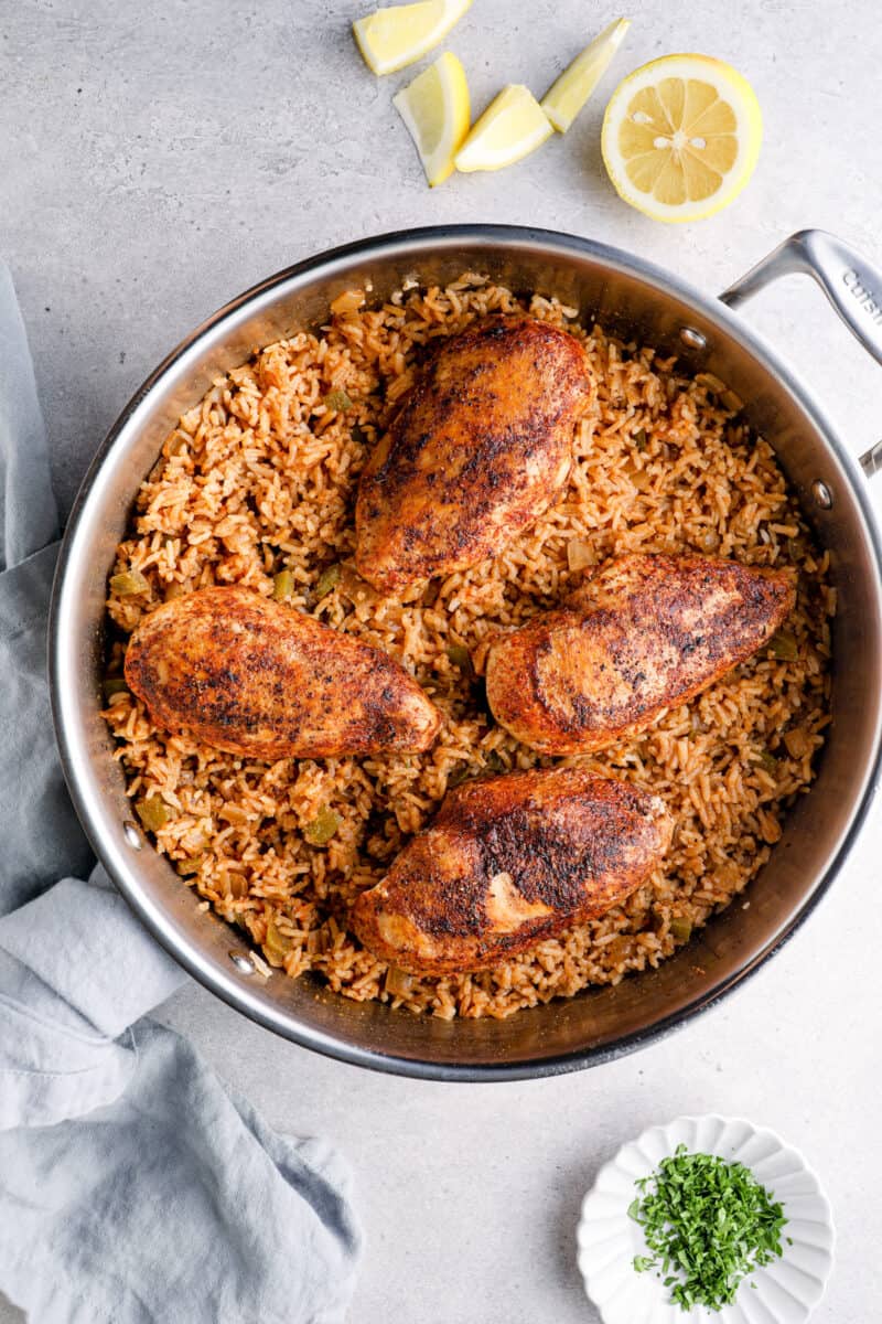 cajun chicken breasts on top of rice in a skillet