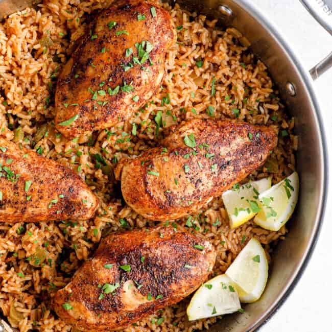 overhead image of cajun chicken breasts on top of rice in a skillet